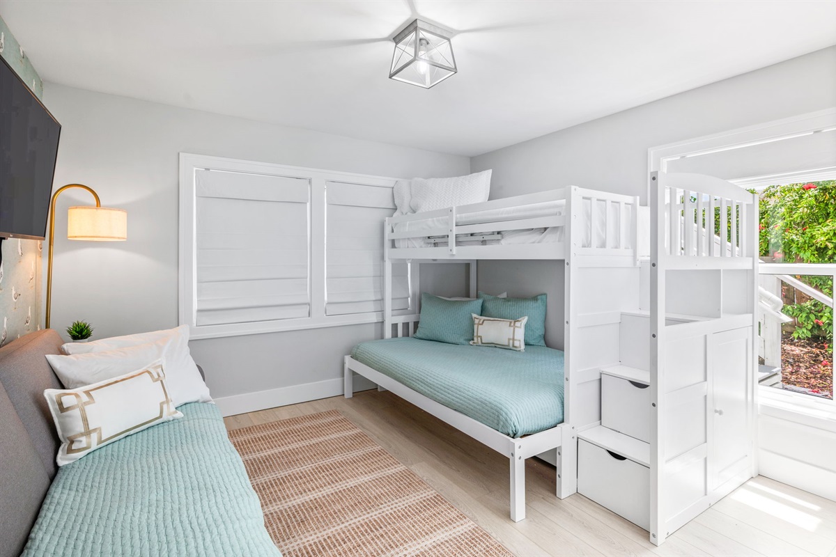 The perfect space for kids or teens! This cozy bunk bed area features a full bed on the bottom, a twin on top, and its own TV with a comfy couch for lounging. While not visible in the picture, the adorable seagull wallpaper adds a playful touch to this fun