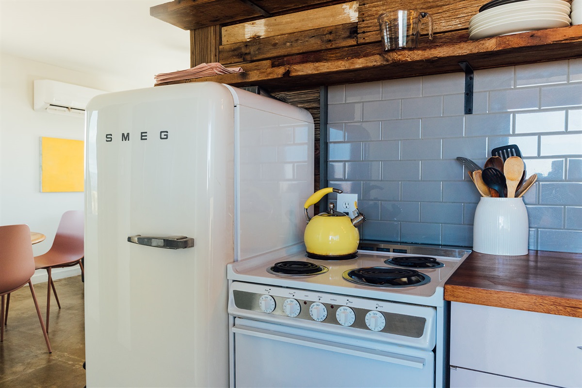 Charming vintage-inspired kitchen featuring a SMEG refrigerator, classic oven, and open shelving with desert-chic touches.