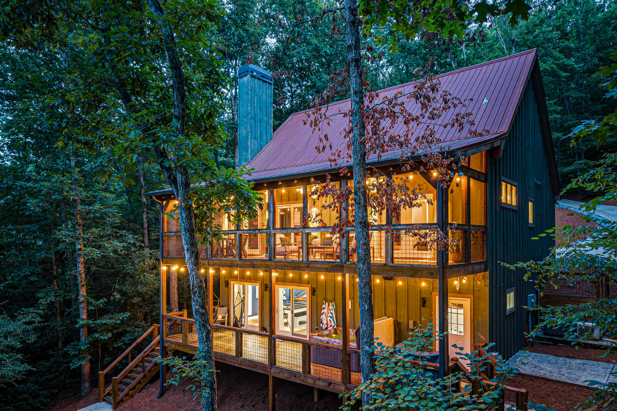 As the sun sets, the cabin transforms into a warm and inviting mountain escape.