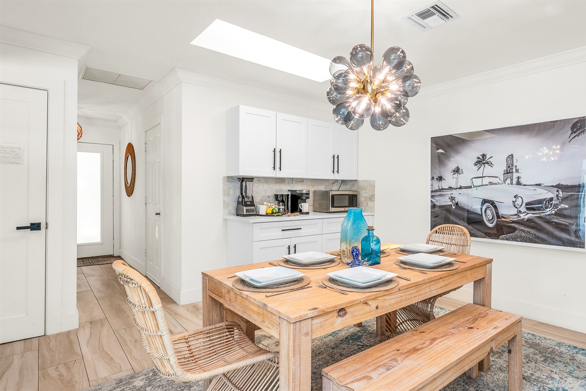 Gather around the rustic wood dining table with seating for six, accented by chic rattan chairs and a statement chandelier. Surrounded by natural light and stylish coastal décor, it’s the perfect space for enjoying meals or entertaining in style.
