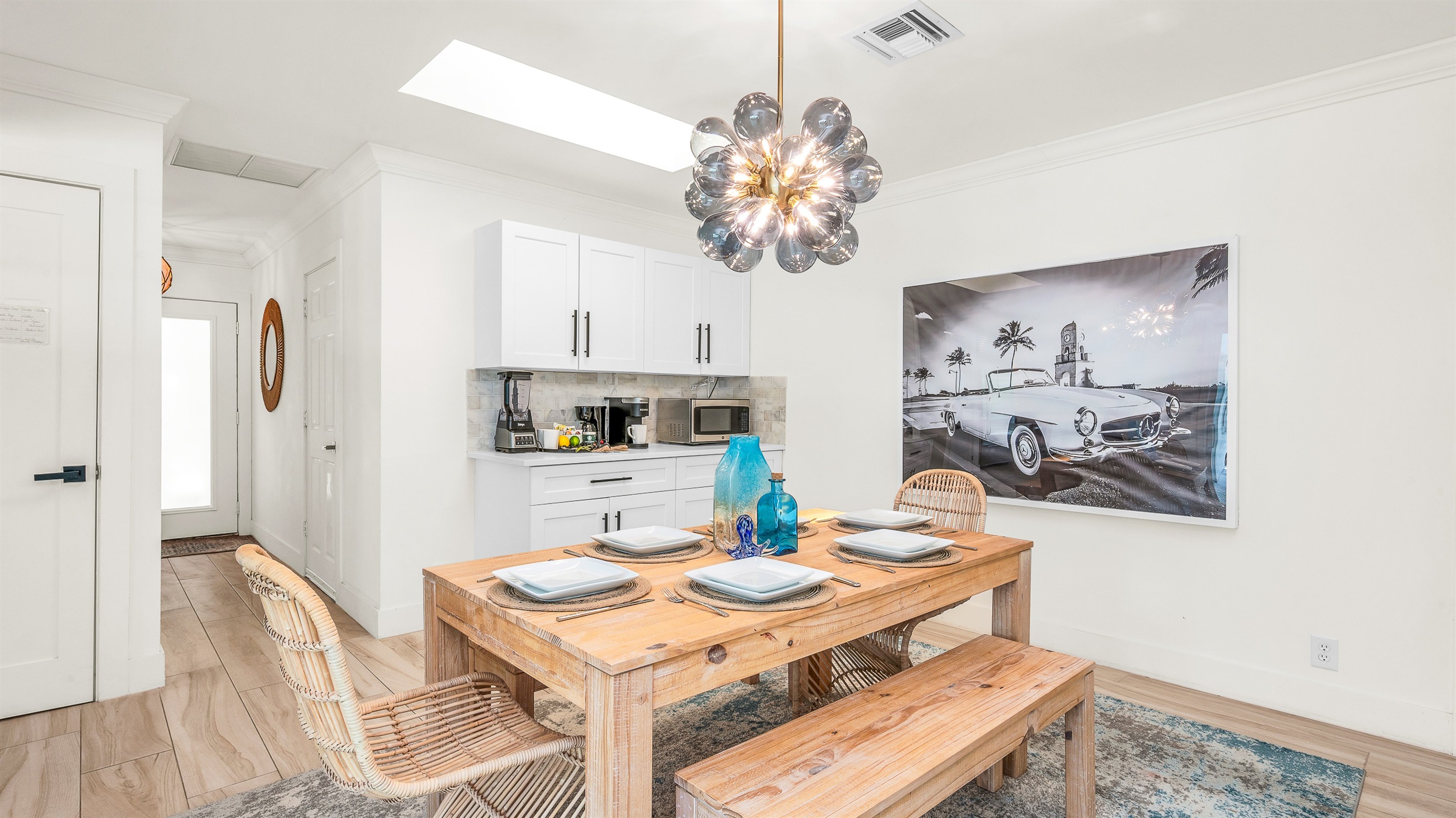Gather around the rustic wood dining table with seating for six, accented by chic rattan chairs and a statement chandelier. Surrounded by natural light and stylish coastal décor, it’s the perfect space for enjoying meals or entertaining in style.
