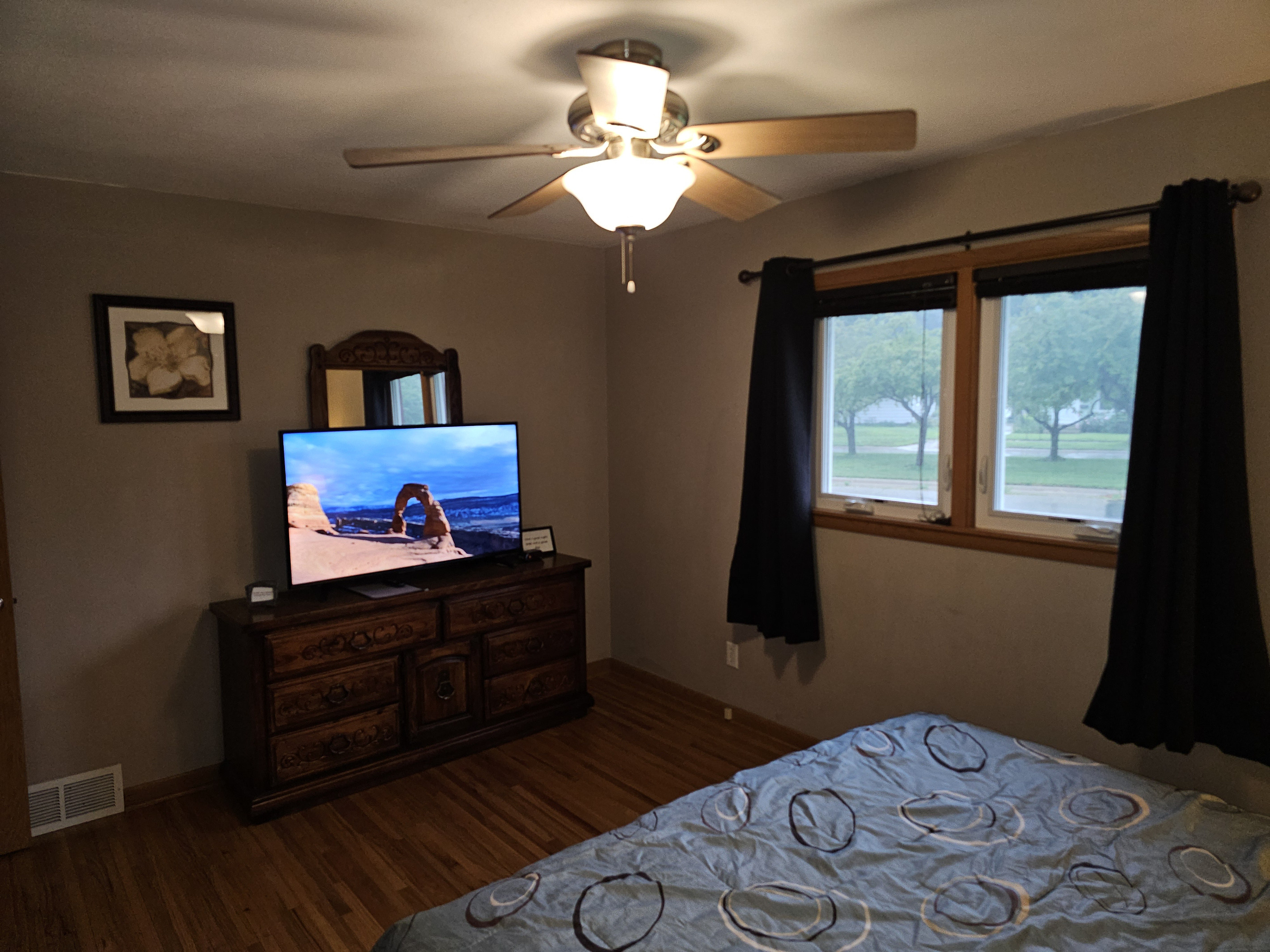 Master bedroom on the main floor with king bed, ceiling fan, alarm clock and a smart tv.