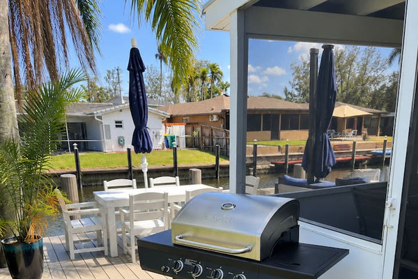 Outdoor gas grill beside the waterfront deck and dining area, perfect for easy cookouts by the canal.