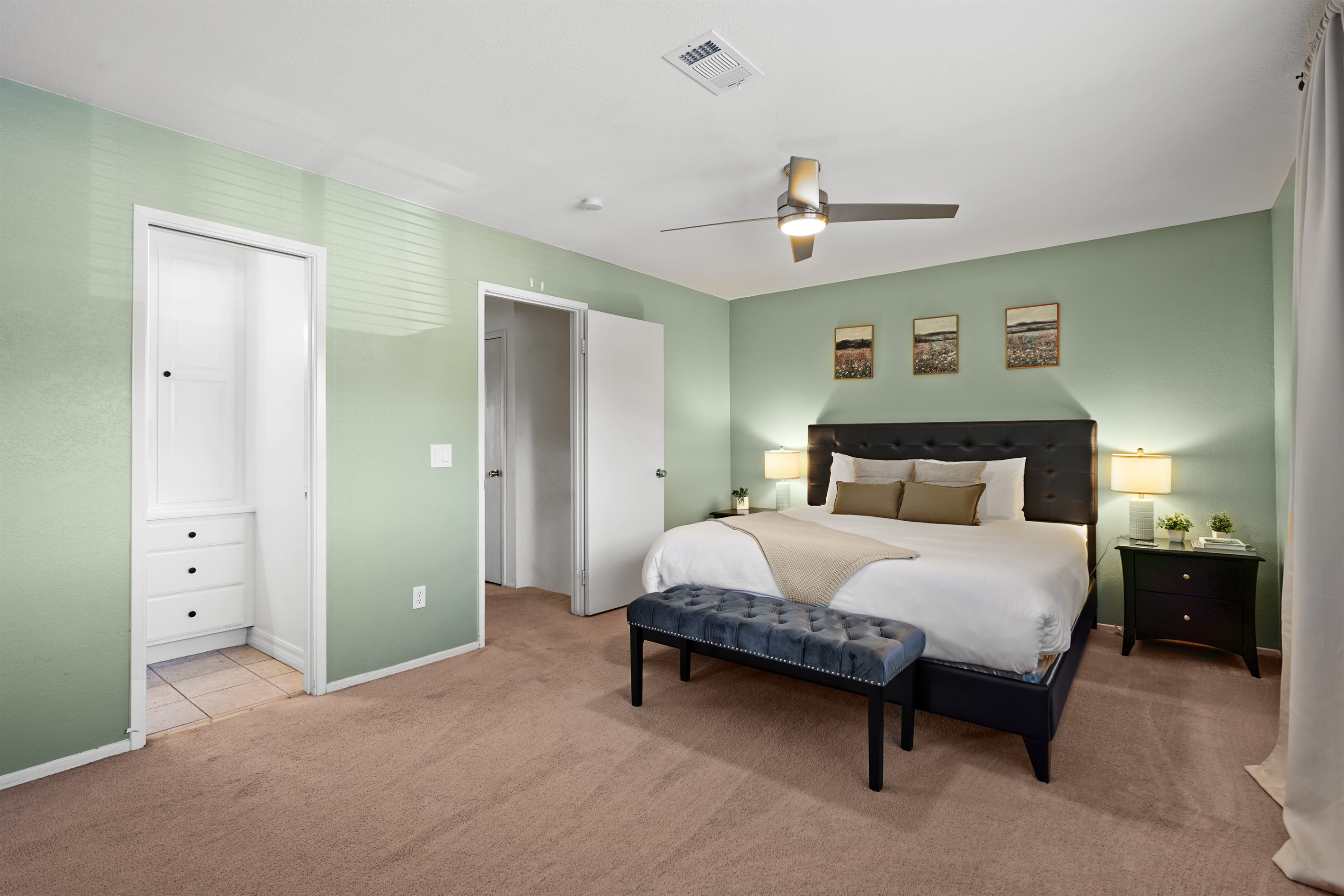 Retreat to the spacious primary bedroom featuring a plush king bed and a calm, relaxing atmosphere.