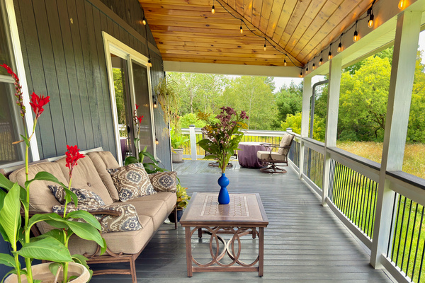 Covered deck with fire pit, cozy seating, and stunning pond and meadow views.
