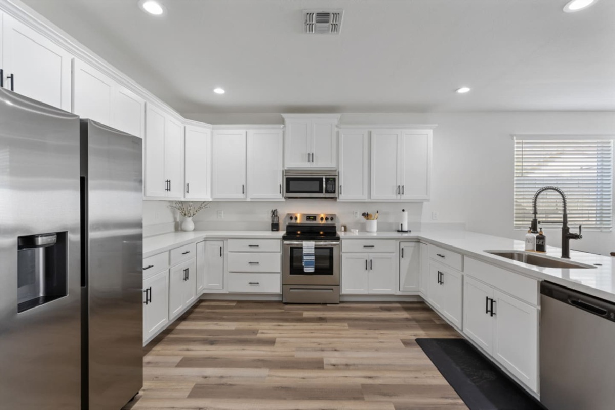 Full kitchen with stainless steel appliances, white cabinetry, dishwasher, and plenty of counter space for everyday meals.