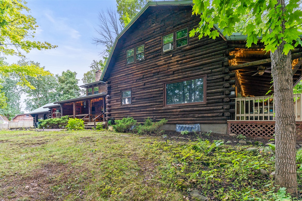Charming log cabin retreat with rustic details, inviting front porch, and serene wooded surroundings—ideal for a cozy getaway.