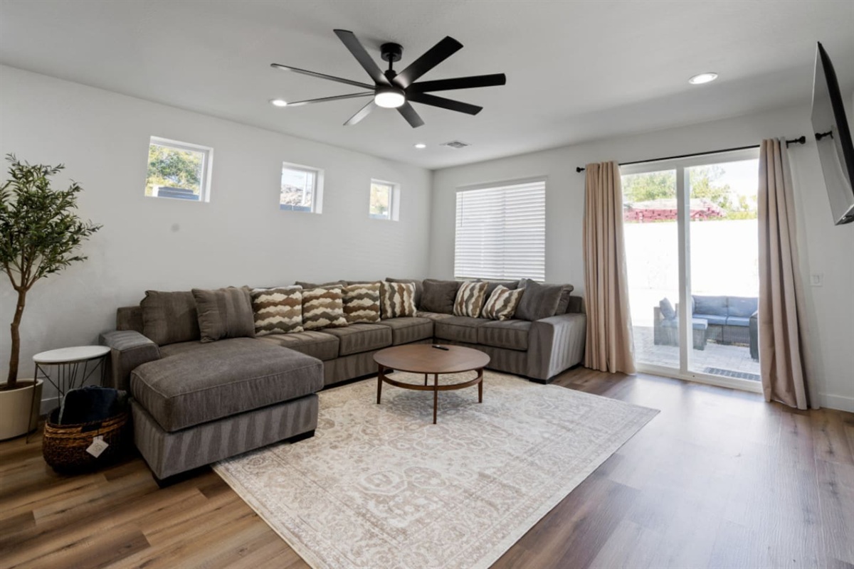 Living room with oversized sectional seating, ceiling fan, natural light, and plenty of space to relax or gather.