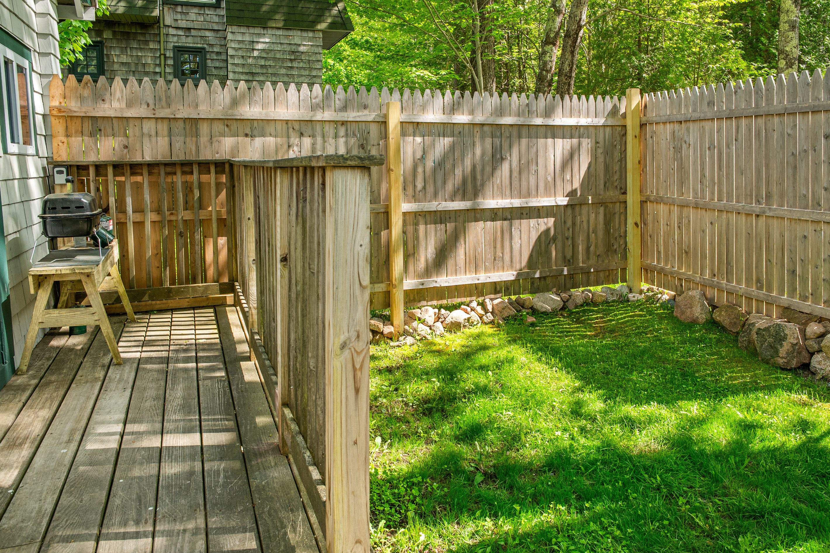 View from the deck showing the convenient layout. Step right from the outdoor grill setup to the partially fenced, grassy yard. A secure, pet-friendly niche designed for easy outdoor living and relaxation at the Davis Outpost.