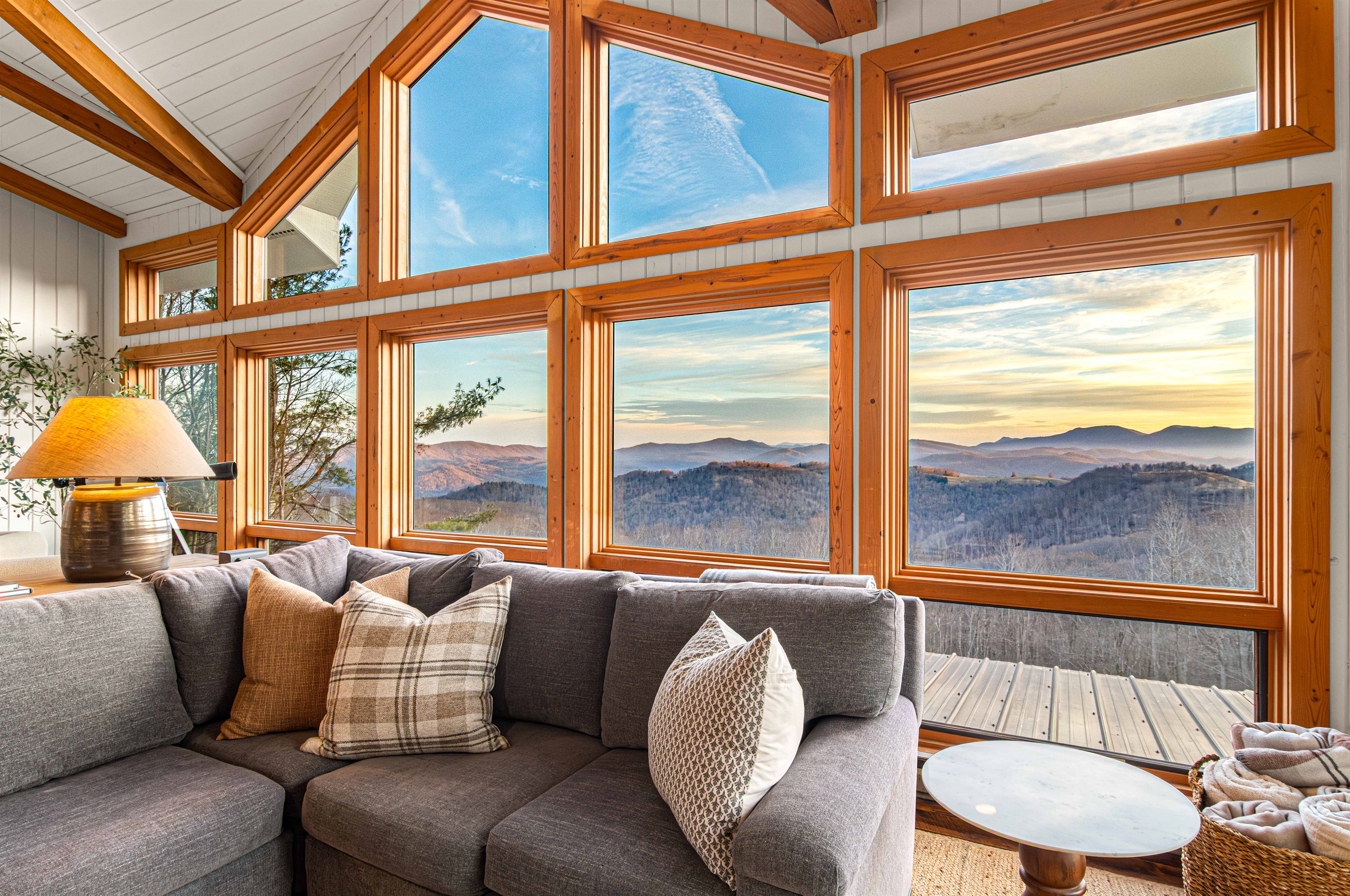 Plush sectional seating wrapped in floor-to-ceiling windows and mountain views.