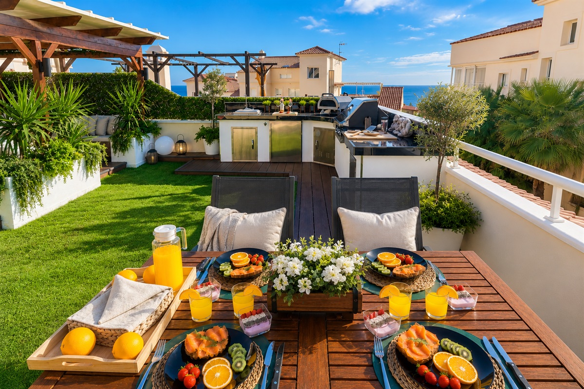 Cook with a view in the fully equipped outdoor kitchen featuring a BBQ, pizza oven, fridge, and sink. Dine al fresco under the open sky surrounded by soft lighting and fresh sea breeze.