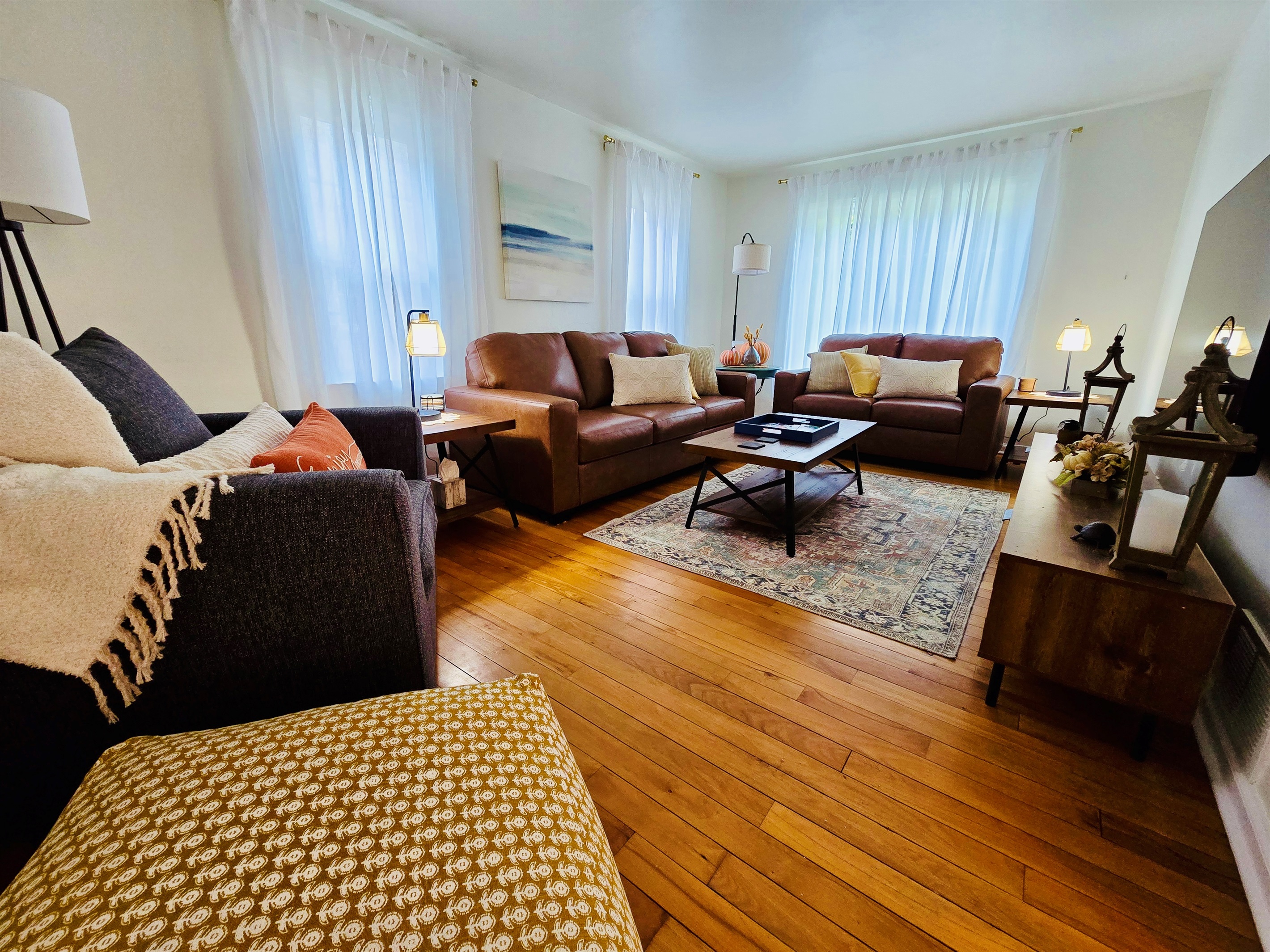 Comfort meets class in our living room—featuring a mounted TV, soft-glow lanterns, and stunning wood floors that anchor the space with timeless charm.