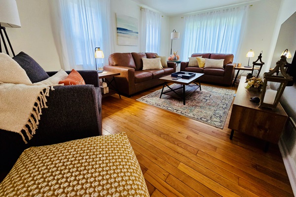 Comfort meets class in our living room—featuring a mounted TV, soft-glow lanterns, and stunning wood floors that anchor the space with timeless charm.