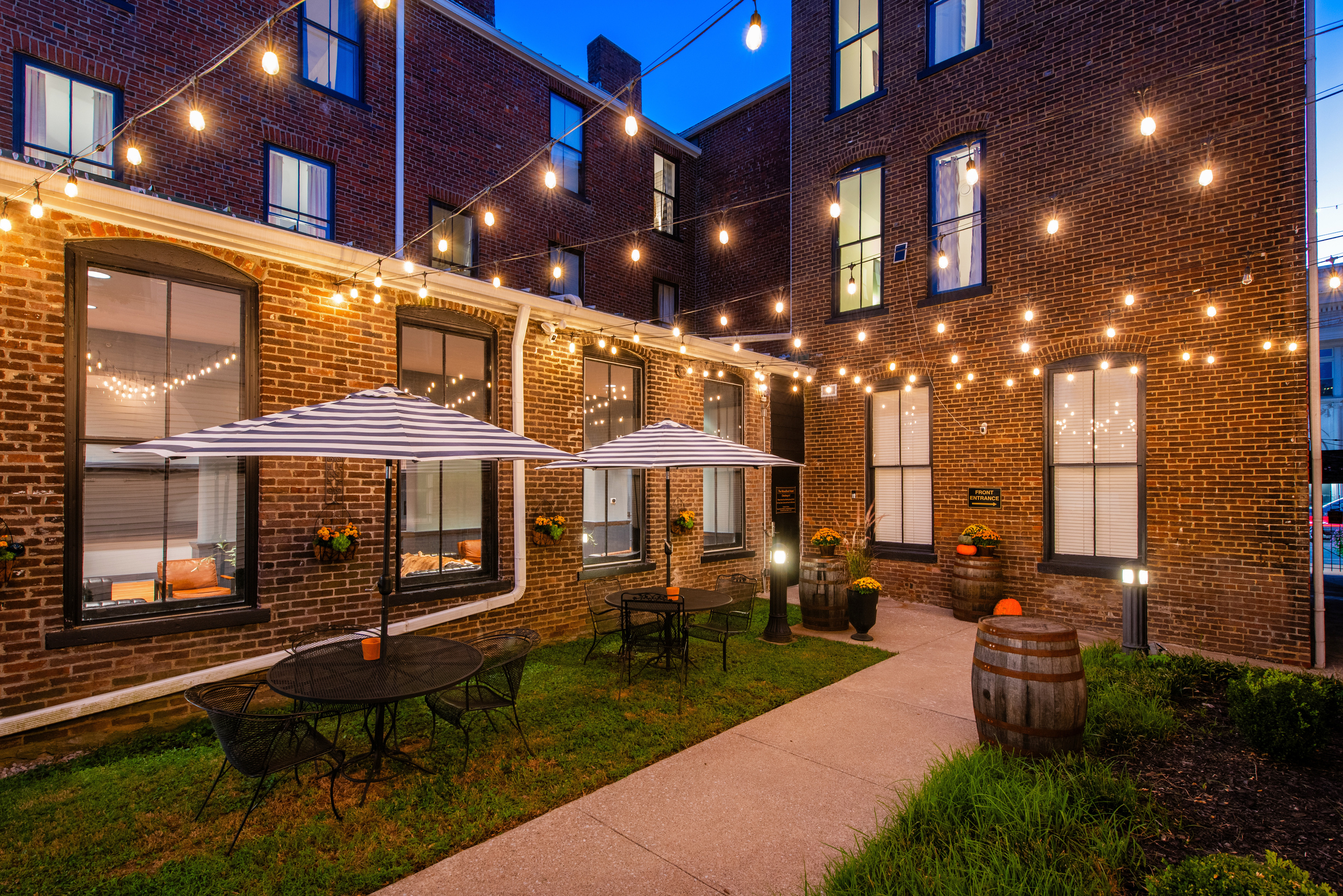 The shared hotel courtyard at dusk, with outdoor tables and string lights.