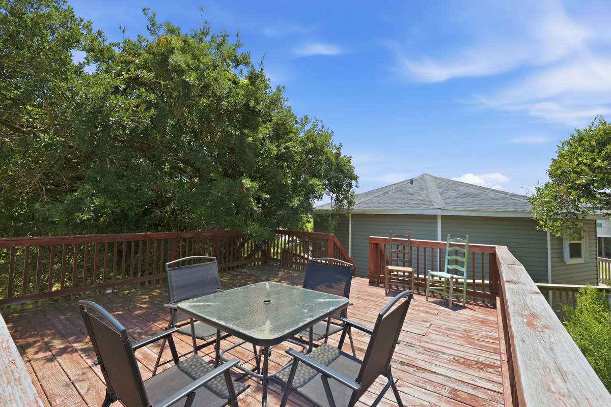 Peaceful upper deck with outdoor dining table, ideal for al fresco meals surrounded by mature trees