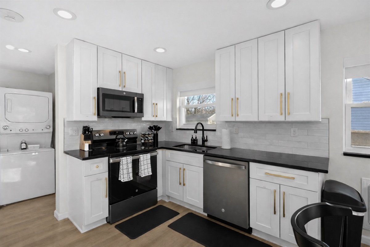 Bright, modern kitchen with crisp white cabinetry, sleek appliances, and in-unit laundry—designed for effortless cooking, convenience, and comfort.