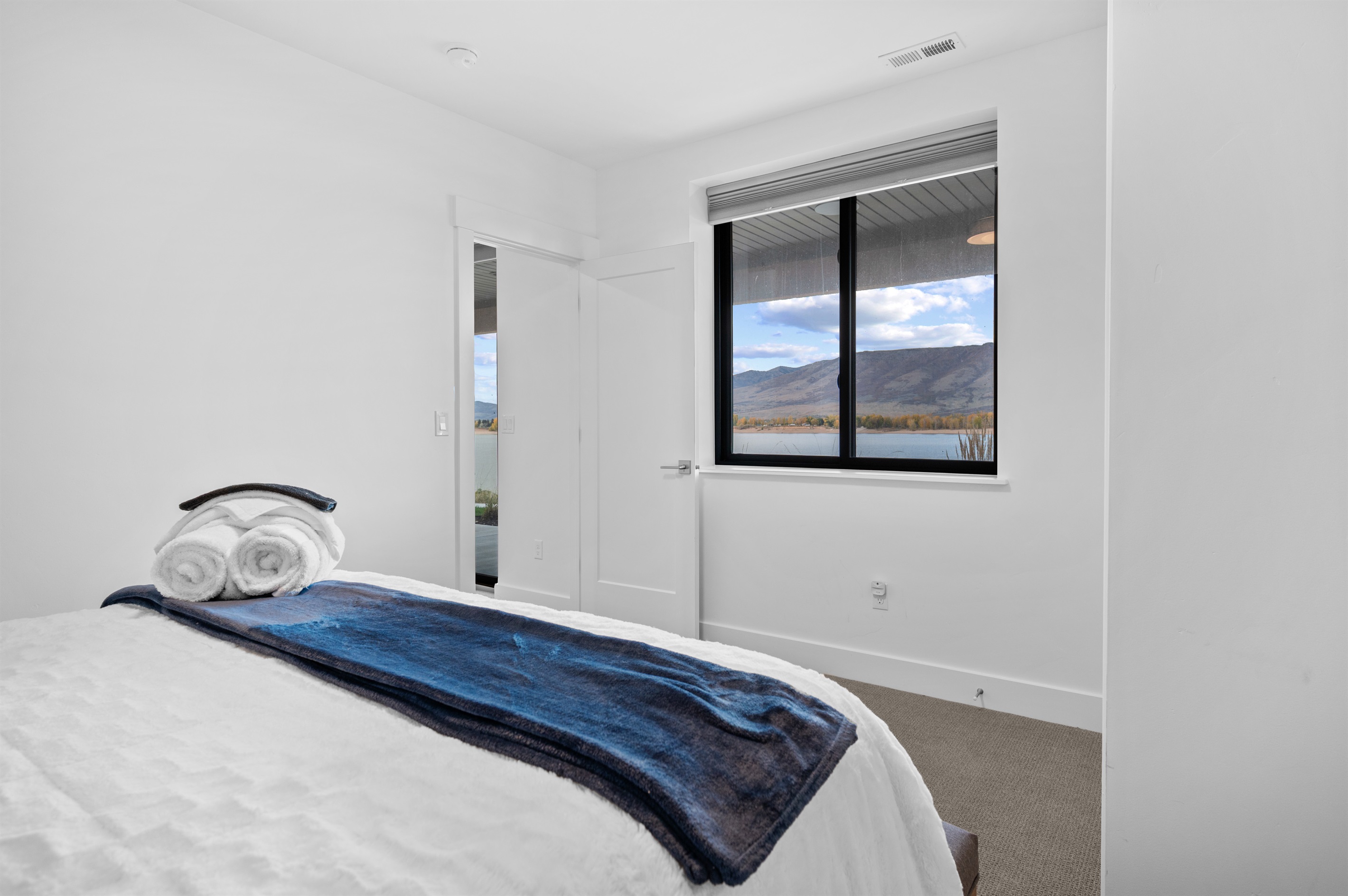 Bright lower-level queen bedroom with window views toward Pineview Reservoir.