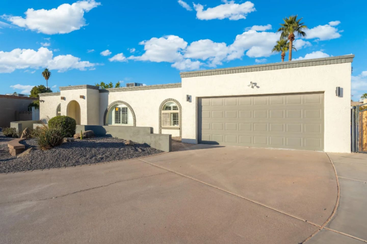 Classic Southwest architecture greets guests from the curb, with clean stucco lines, arched windows, and a spacious driveway that fits the whole group's cars with room to spare.
