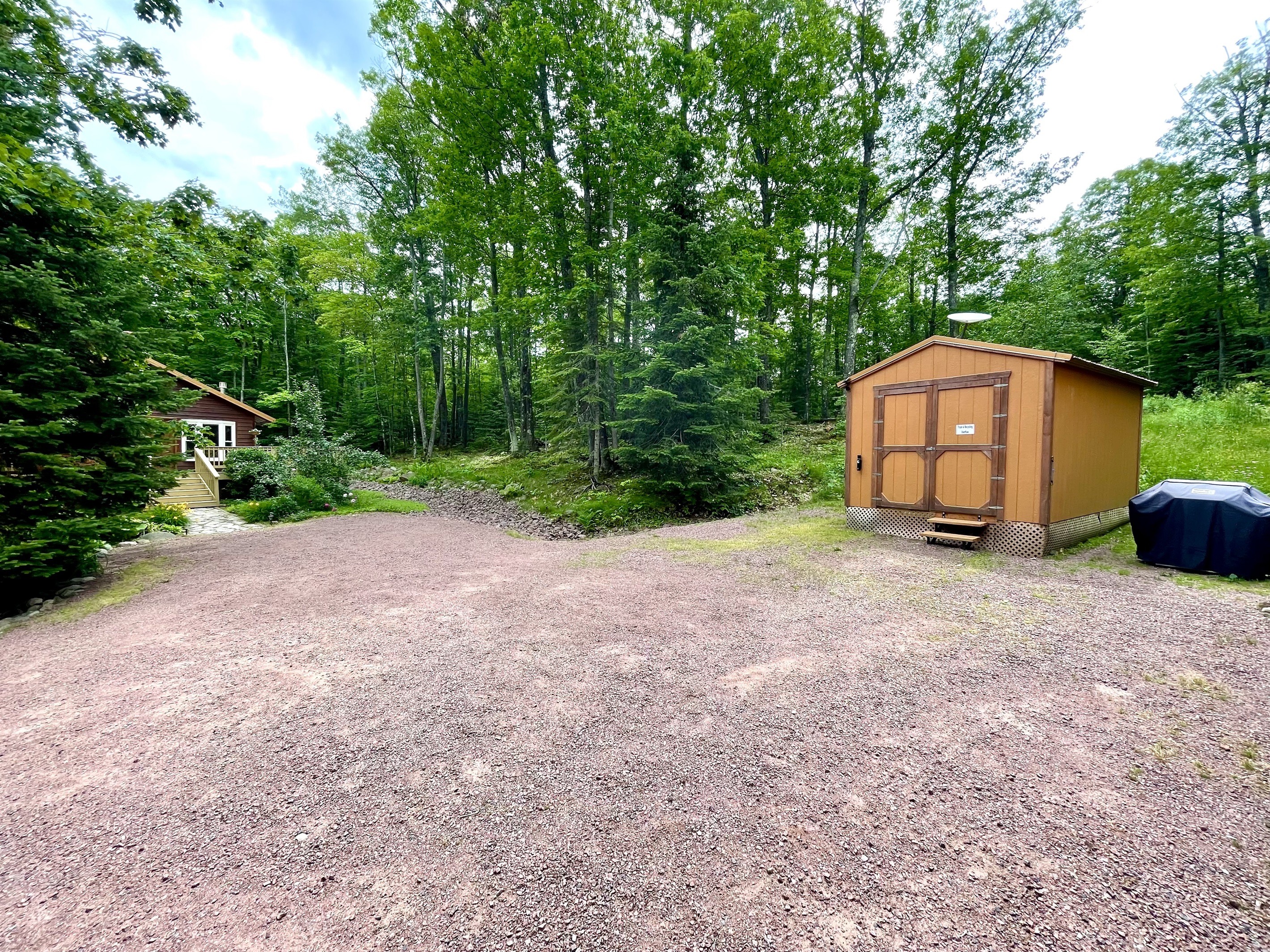 View from front door of cottage looking to driveway grill available for year-round use, the other 2nd cottage “main cottage” is 100ft away limited views pine trees and one window faces cottage with blinds for privacy 