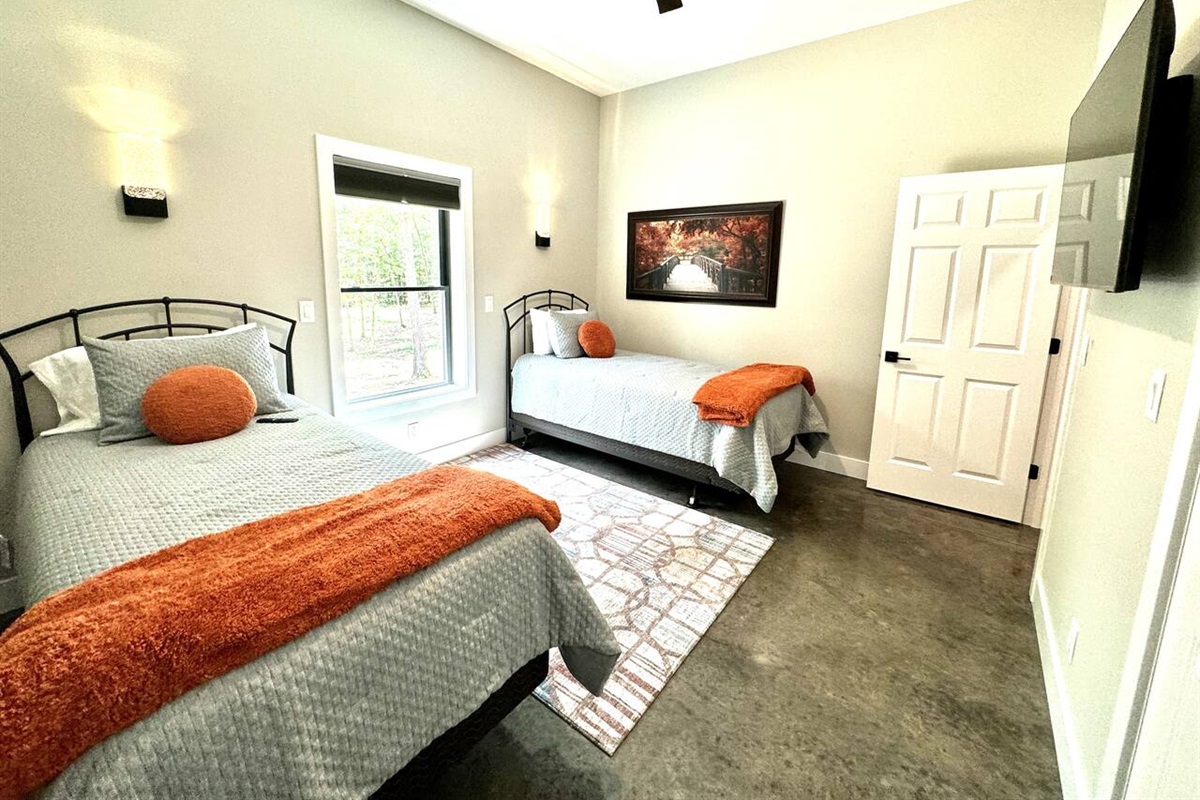 Wall sconces and a large ceiling fan provide ample lighting. This bedroom has two windows to view large trees lots outside.
