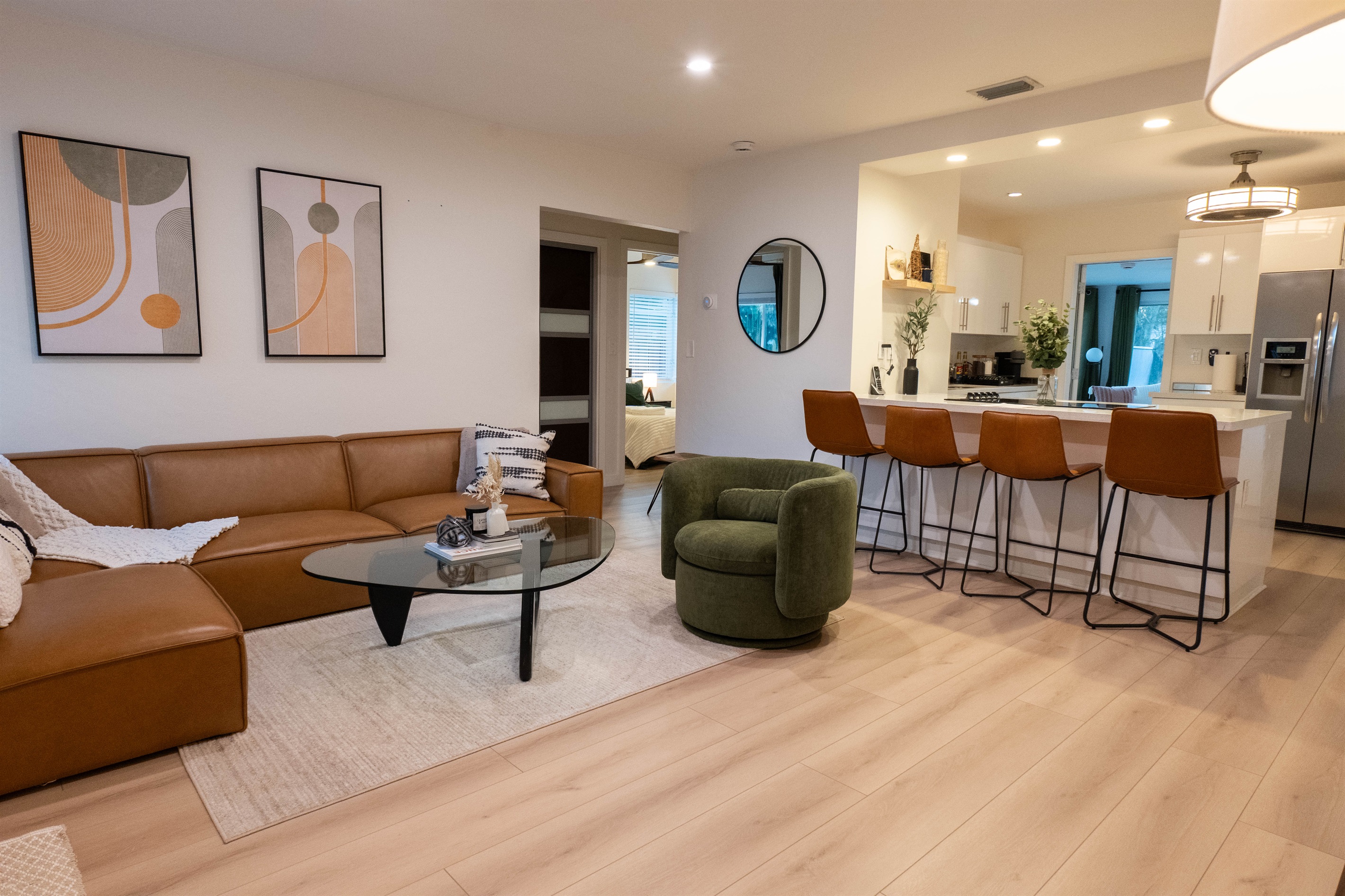 Open living area with sectional sofa, swivel chair, and kitchen bar seating