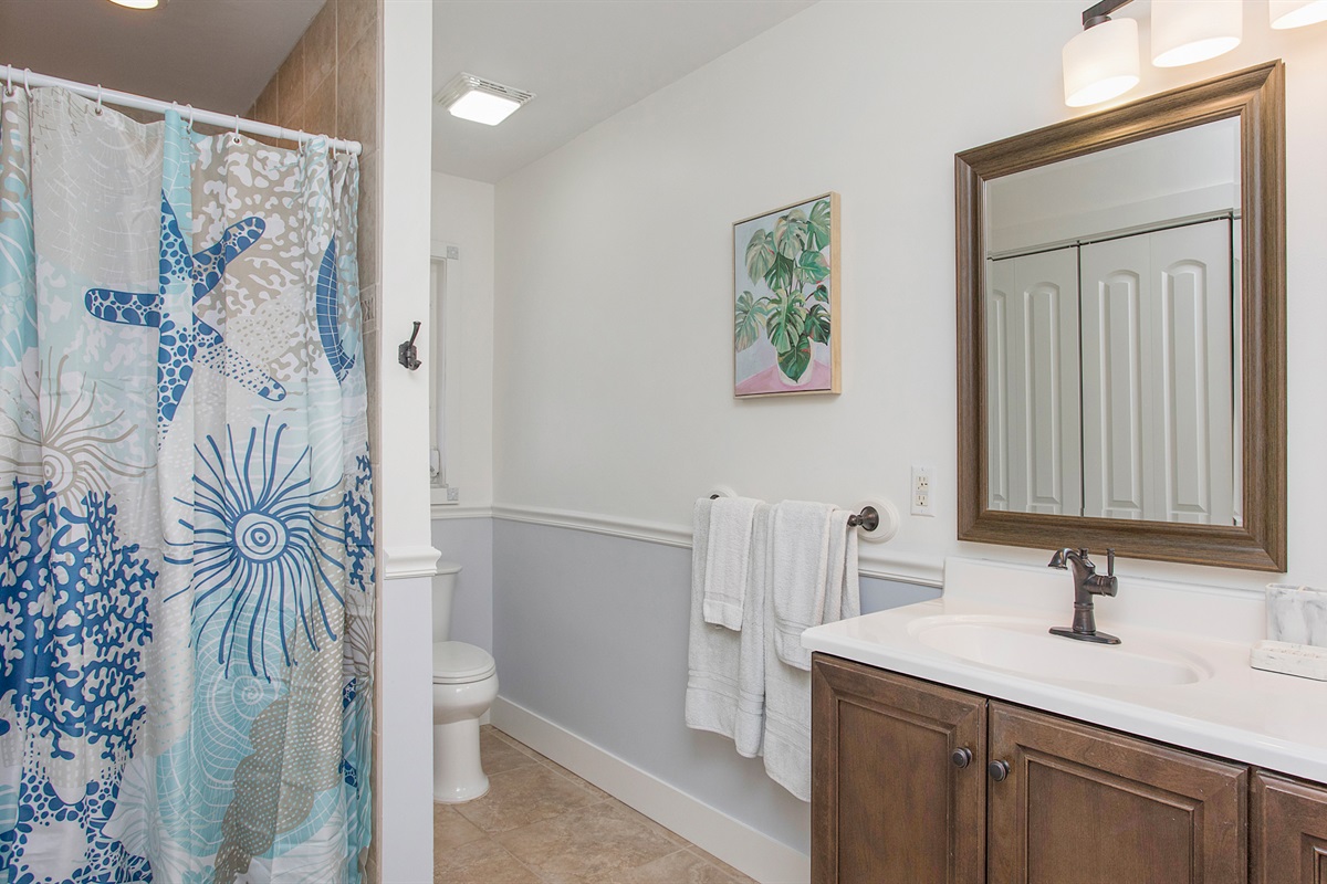 Bathroom with shower, toilet, and his and her vanities.