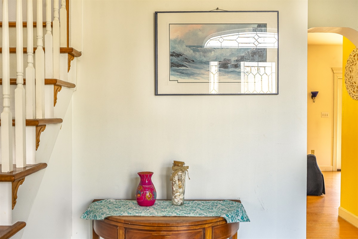 Experience a warm Maine welcome the moment you walk through the door. This charming foyer nook, tucked beside the grand staircase, showcases the home's thoughtful details and leads you directly into the main living spaces of your Acadia retreat.