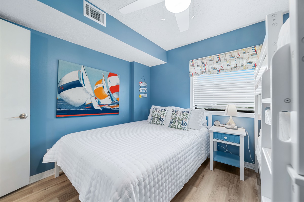 This well-appointed guest room offers a queen-size bed and a bunk bed, soft lighting, and a window providing natural light and a pleasant outlook.