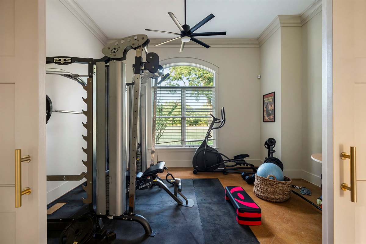 Stay active without leaving the house in a bright fitness room featuring a multi-station weight machine, elliptical, bench, and a variety of free weights. Additional equipment includes a stability ball, step platform, and resistance accessories.
