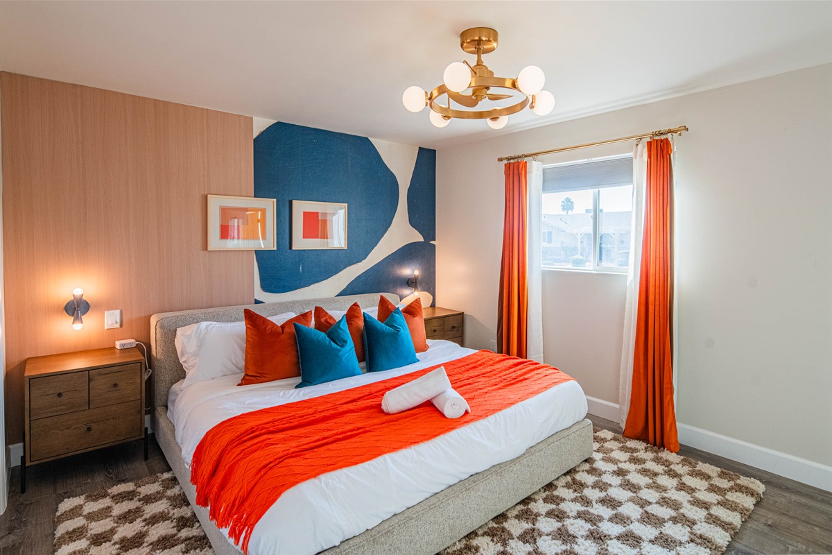 Beautifully styled ensuite guest bedroom with a king bed, vibrant décor, and cozy furnishings — perfect for couples or solo travelers.
