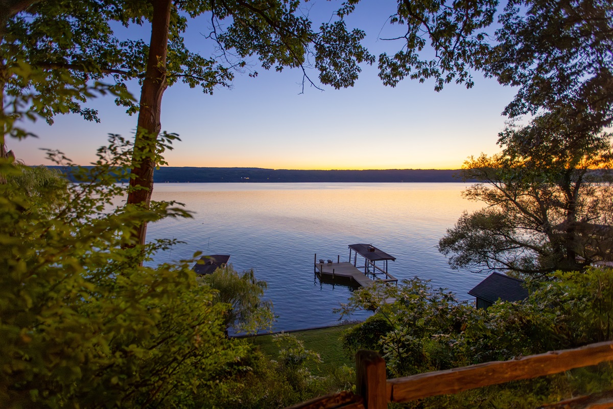 Two flights of stairs lead down the flat grass beach area, the boathouse, and permanent dock with electric boat lift | Boat lift available for use with owner permission
