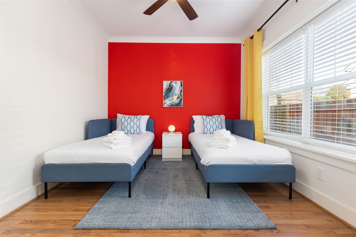 First floor twin room features blackout curtains, overhead fan, and dedicated work space. 3 additional bedrooms upstairs! 