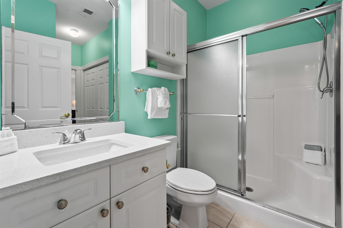 A modern washroom featuring a sleek glass partition, a bright white wooden cabinet, and coastally fixtures—combining functionality and simplicity for a refreshing experience.