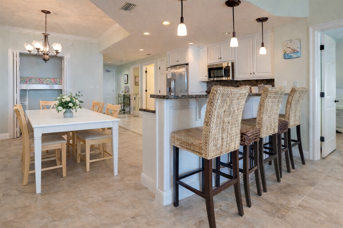 Modern beachside dining made easy: dining table, breakfast bar with extra seating, and an open layout for connecting, cooking, and entertaining in style.