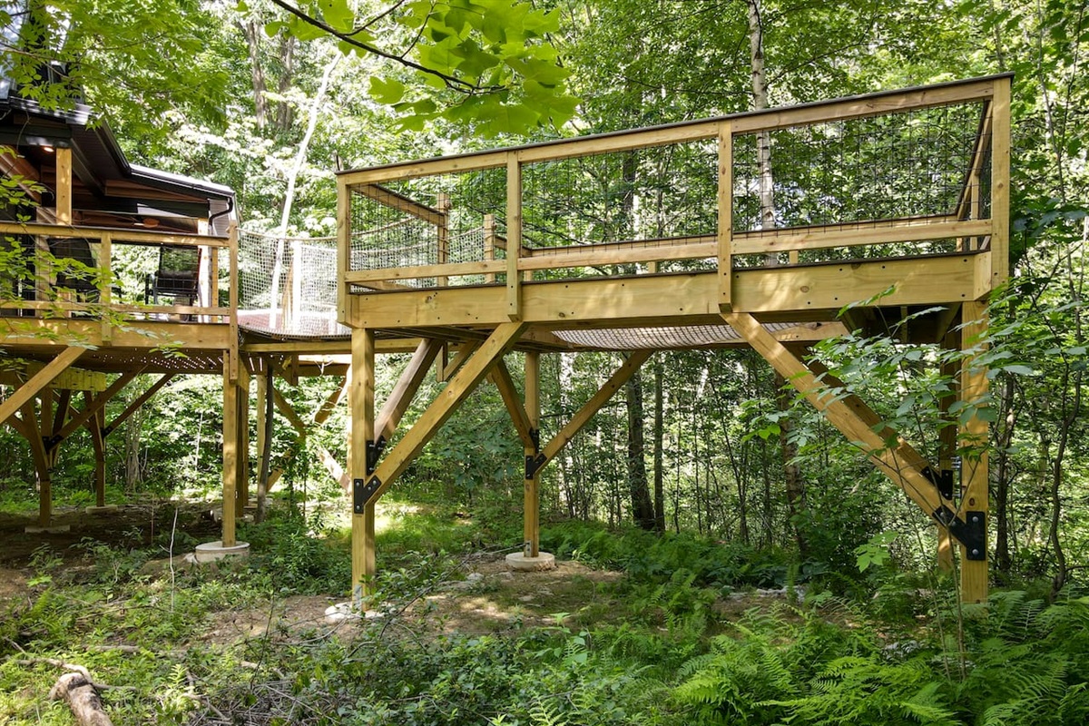 This unique treehouse deck offers a luxurious outdoor experience with an elevated hot tub and XL hammock seamlessly built into the deck floor. Additionally, enjoy the refreshing outdoor shower while surrounded by nature, making it a perfect retreat.