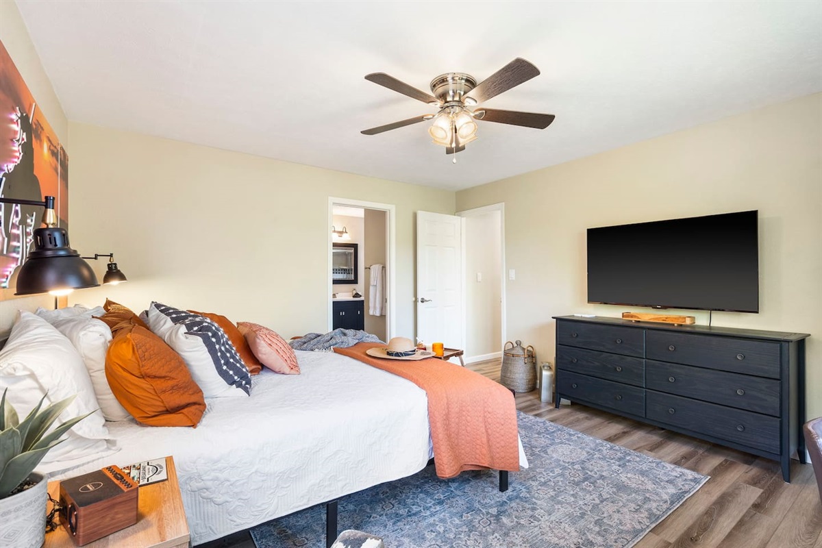 Bright king bedroom with TV and modern rustic decor. 