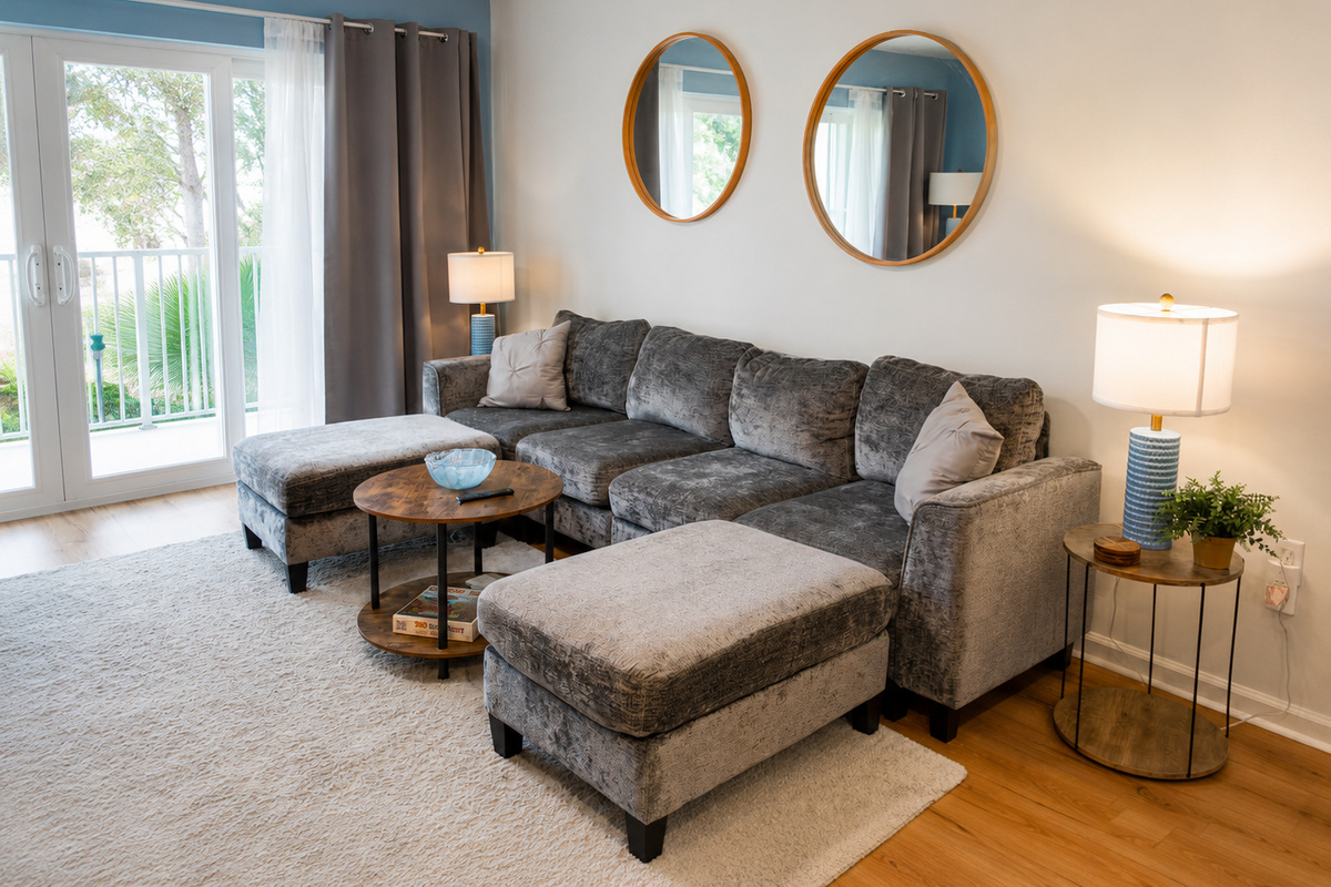 Modern living room with gray sectional, round mirrors, and bright natural light.