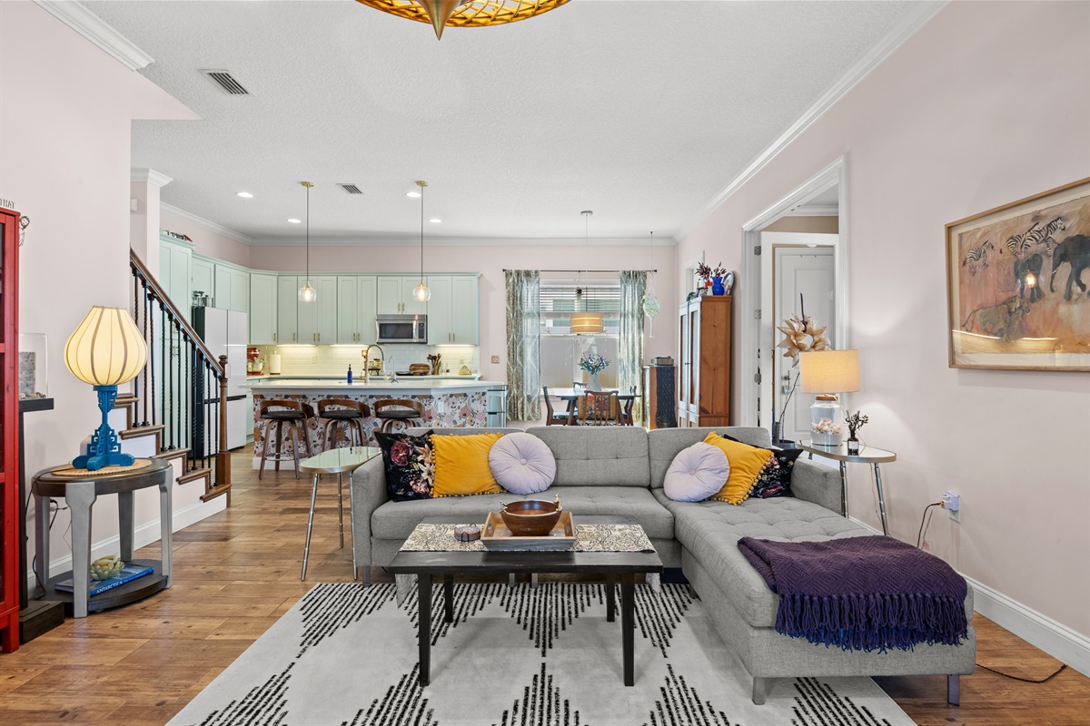 Cozy living room with sectional sofa and view of mint‑green kitchen in Jacksonville Beach rental property.