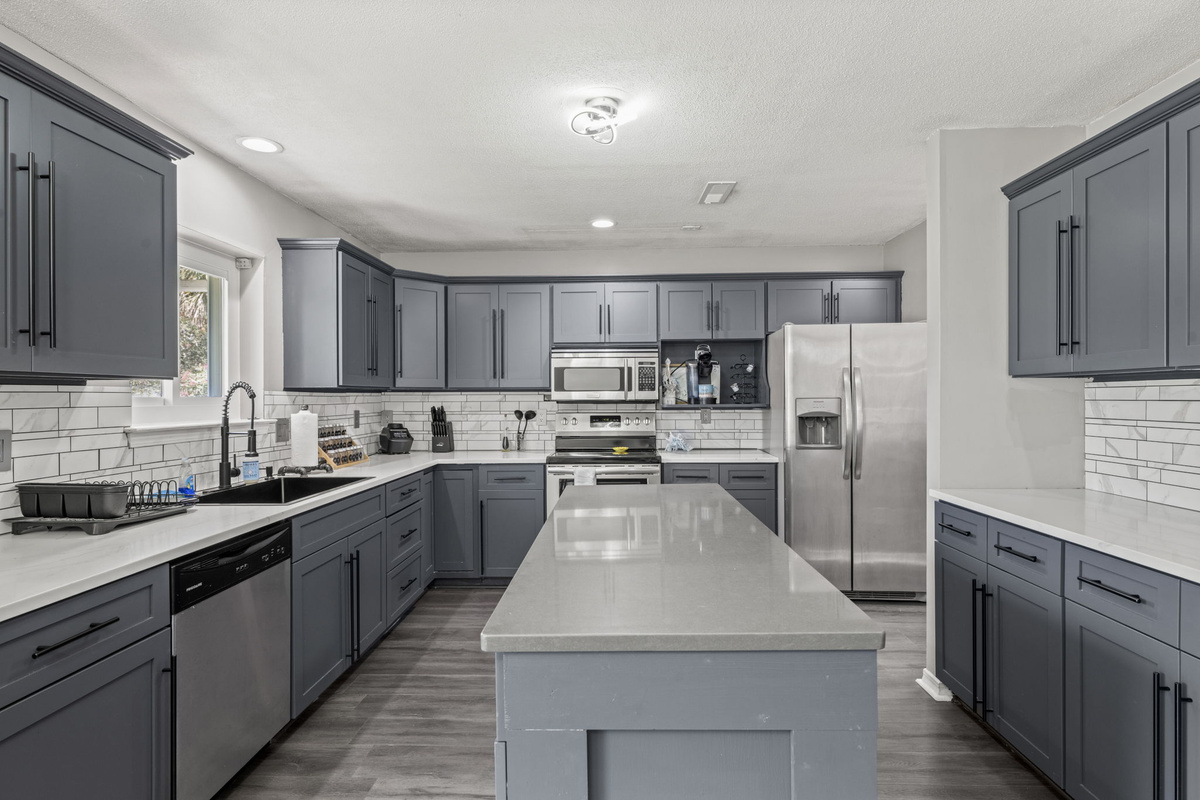 A chef's dream — spacious island seating, sleek gray cabinetry, and stainless steel appliances throughout.
