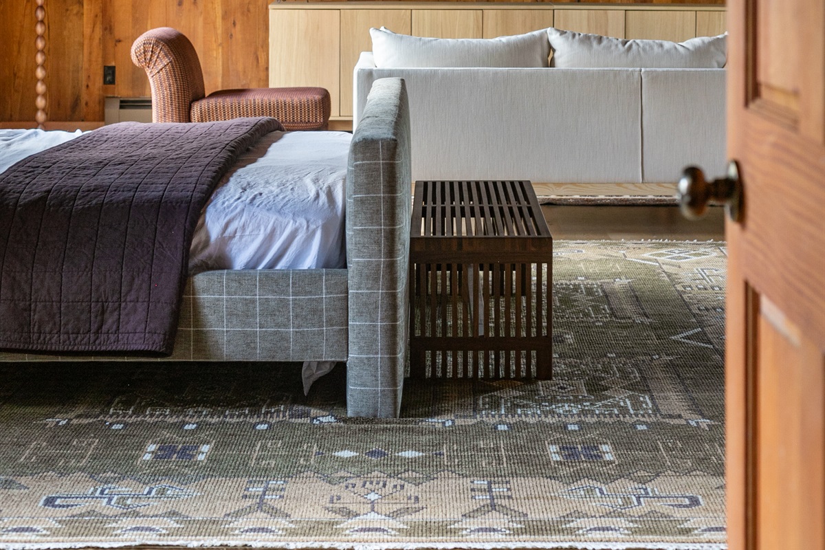 At the foot of the bed, a modern bench adds both style and function — the perfect spot to set your bag, slip on shoes, or simply pause and take in the cozy space.