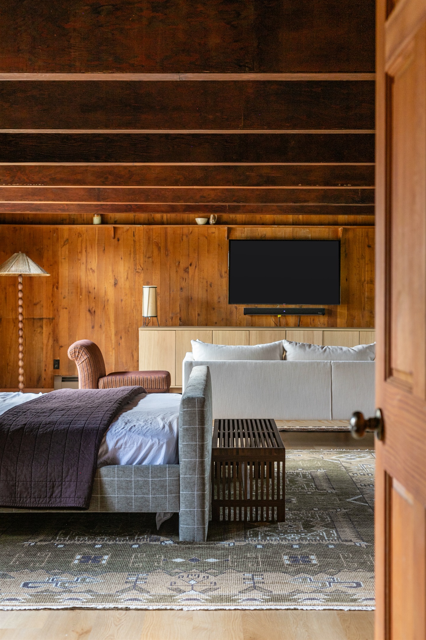 At the foot of the bed, a modern bench adds both style and function — the perfect spot to set your bag, slip on shoes, or simply pause and take in the cozy space.