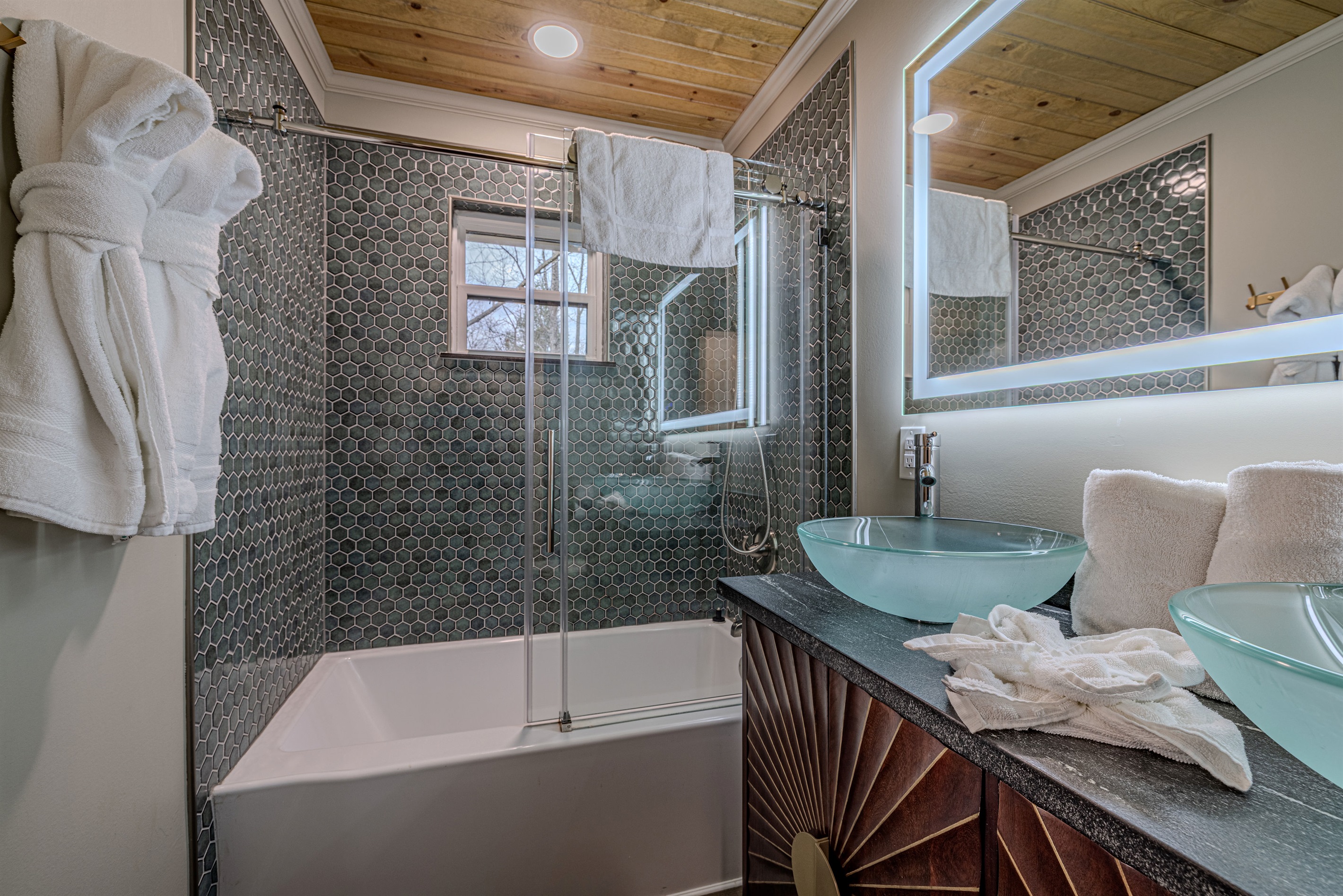 Enjoy a soak in our modern tub, surrounded by beautiful honeycomb tiling and a tranquil view of the mountain trees outside.