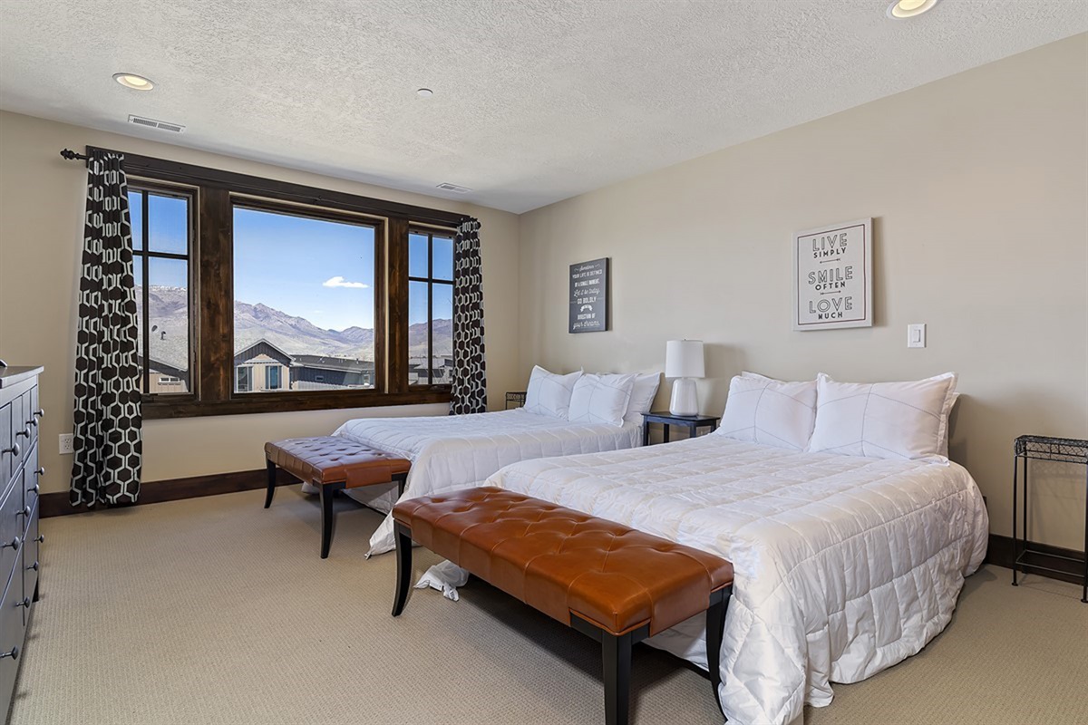 A stylish second bedroom featuring two full beds and picturesque mountain views, offering both comfort and versatility for guests.
