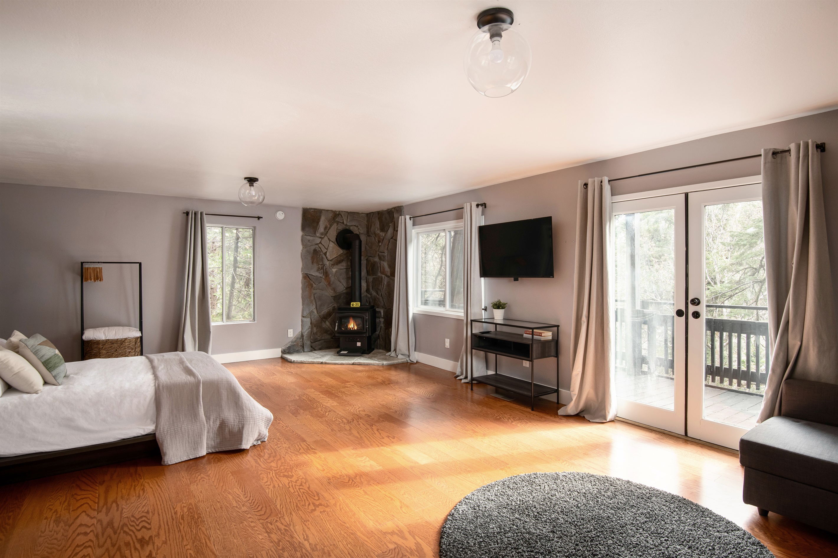 Spacious primary bedroom with cozy fireplace, private deck access, and plenty of natural light—your own peaceful retreat in the trees.