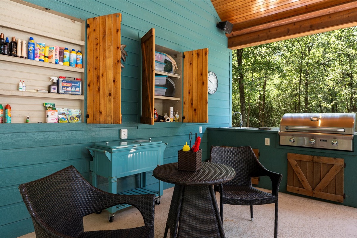 A well-stocked outdoor kitchen designed for convenience and relaxation! Equipped with a grill, seating area, and essentials like sunscreen and pool toys, this space is perfect for cooking, dining, and enjoying the outdoors in comfort