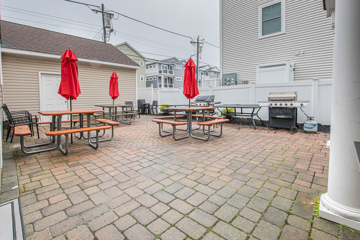Outdoor Paver Patio with Picnic Tables, Red Umbrellas, and Grill