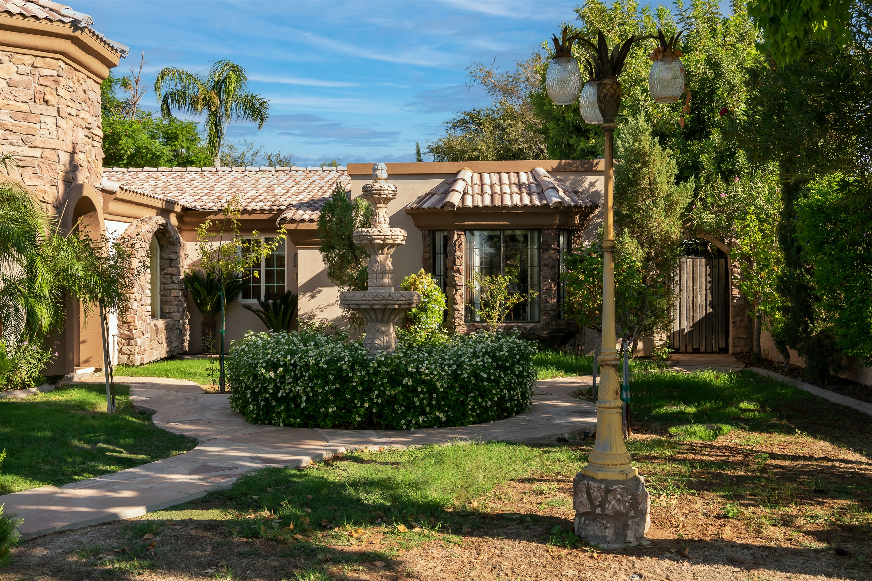 Lush landscaping and a sunlit courtyard welcome you to this elegant desert retreat with timeless architectural beauty.