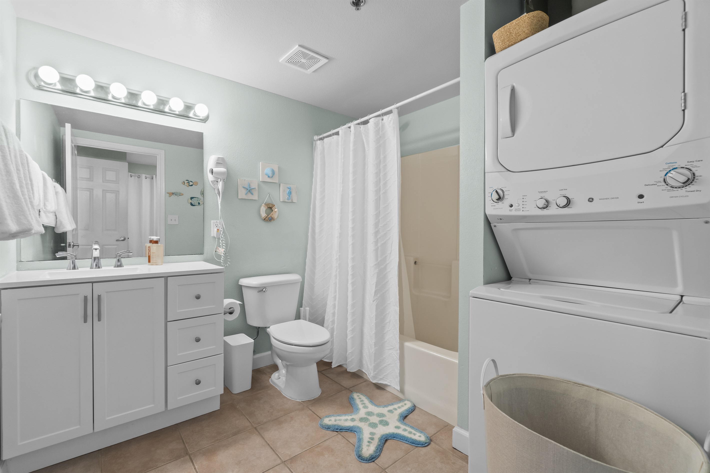 Full guest bathroom with shower/tub combo and a stacked washer and dryer unit for your laundry needs.