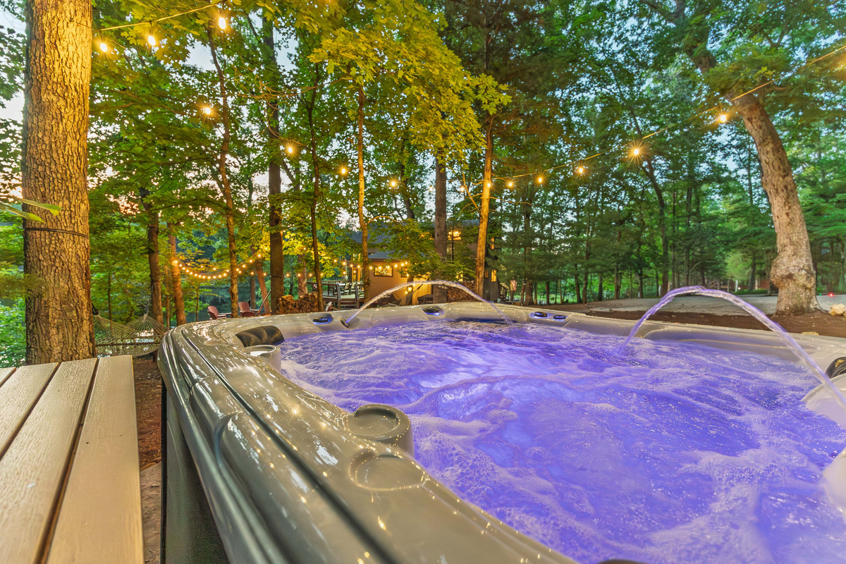 Relax in the lakeside hot tub beneath string lights and the trees.