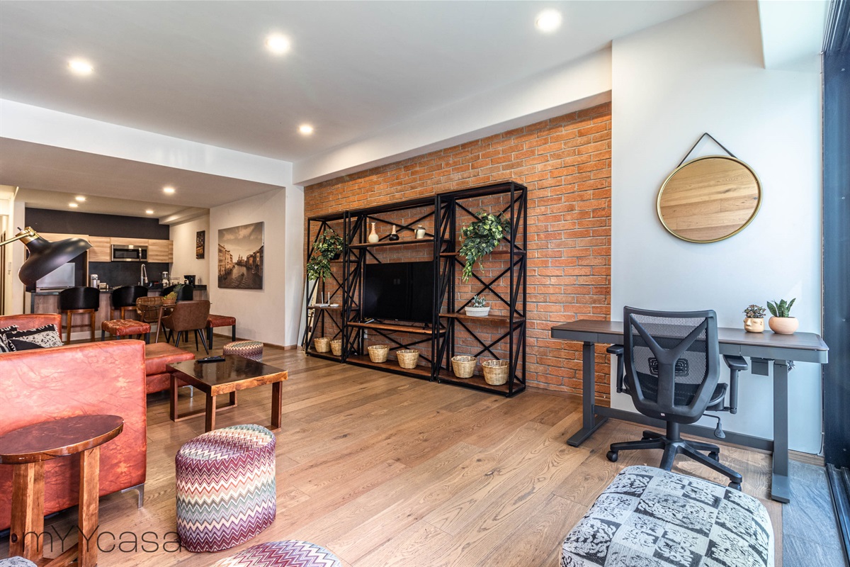 Spacious living room with TV and dedicated electronic desk, offering comfort and productivity